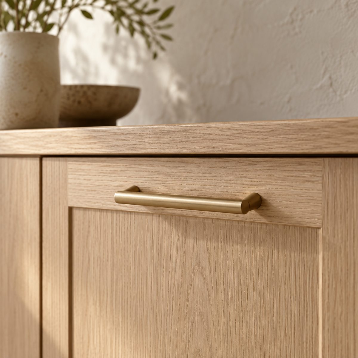 A brushed-brass pull on an oak drawer.